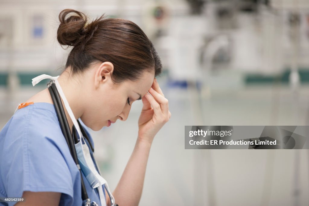 Nurse rubbing her forehead in hospital
