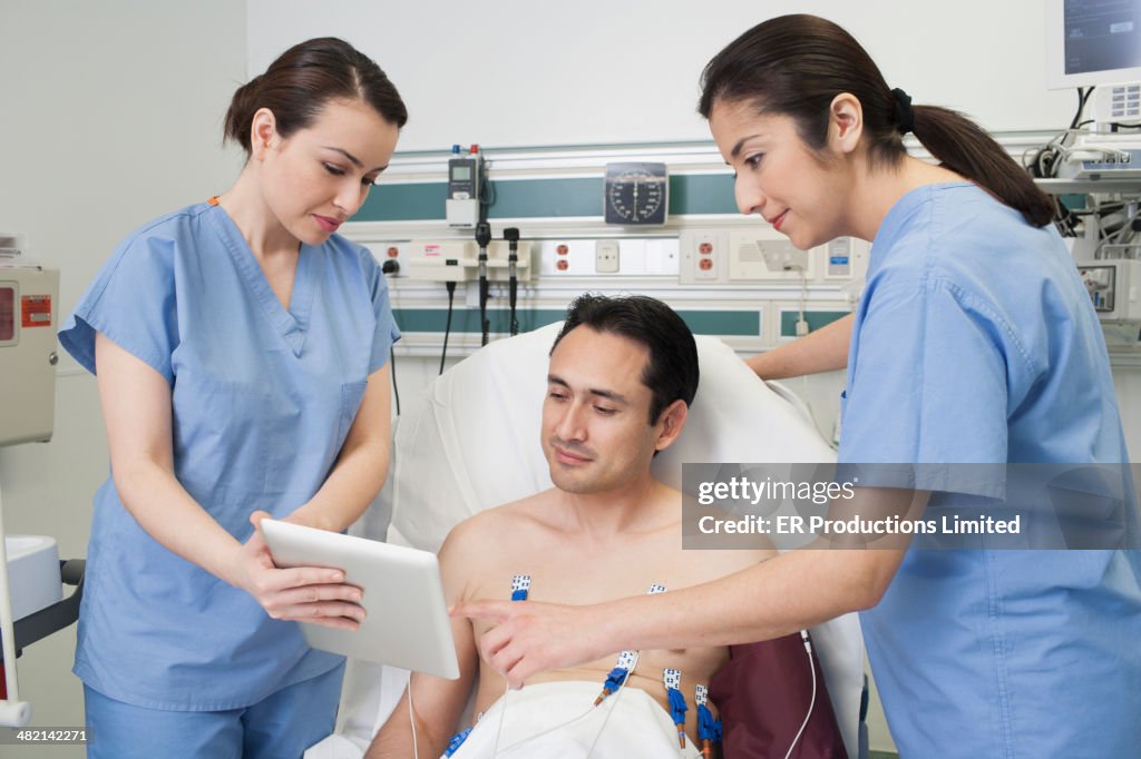 Nurses and patient using digital tablet in hospital