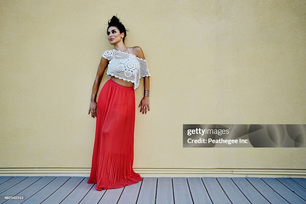 Middle Eastern woman leaning against wall outdoors