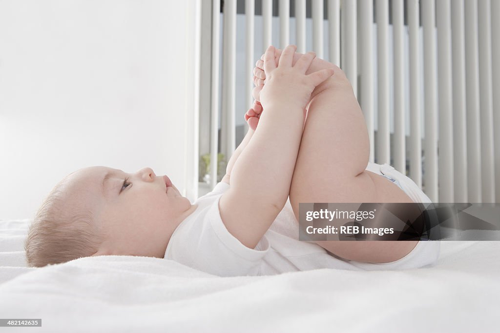 Hispanic baby boy playing with feet