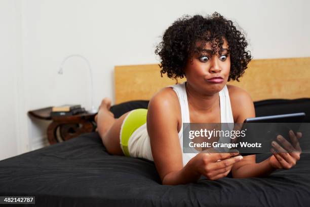 mixed race woman using digital tablet on bed - surprised woman looking at tablet stock pictures, royalty-free photos & images