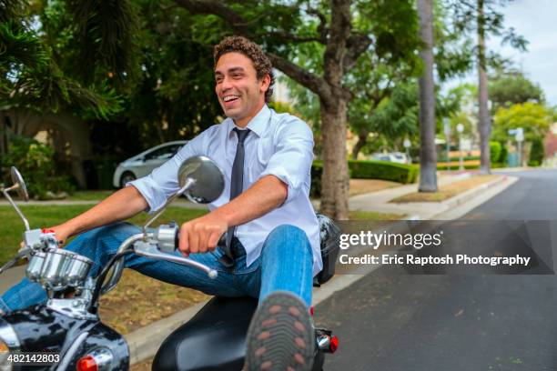 hispanic businessman driving moped on neighborhood road - riding vespa stock pictures, royalty-free photos & images