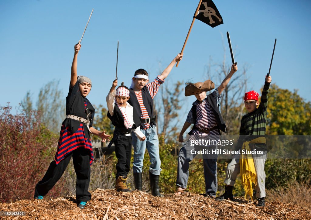 Boys in pirate costumes holding swords and flag