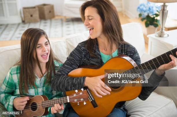 caucasian mother and daughter singing with guitar and ukulele - デュエット ストックフォトと画像