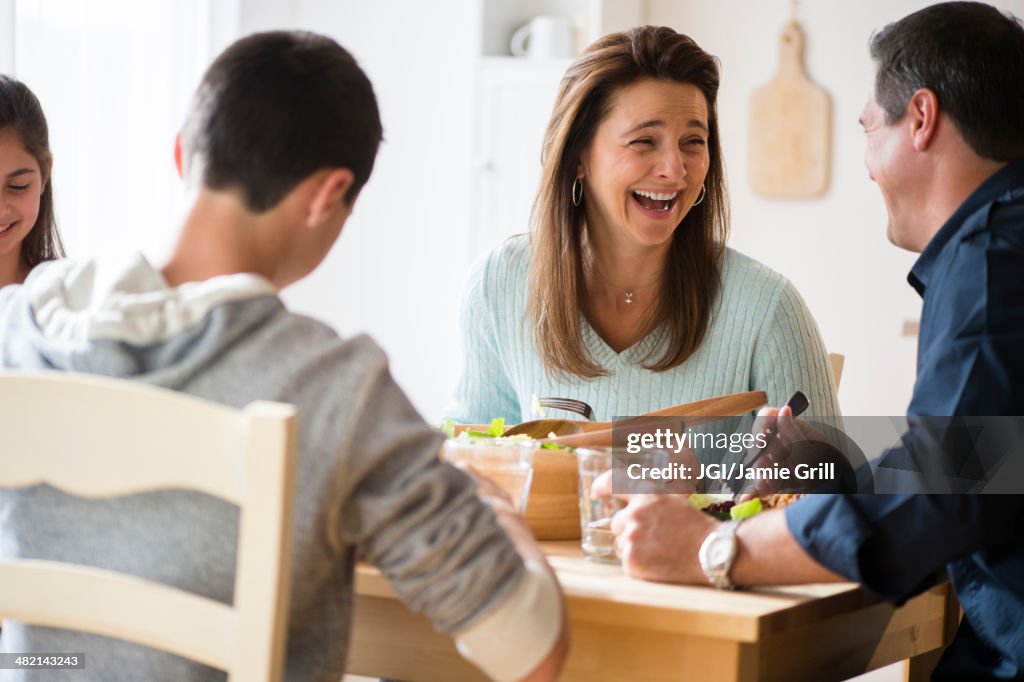 Caucasian family laughing and eating at table