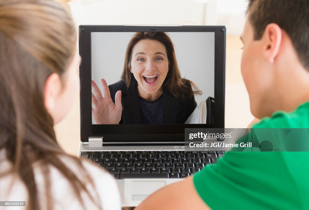 Caucasian children video conferencing with mother on laptop