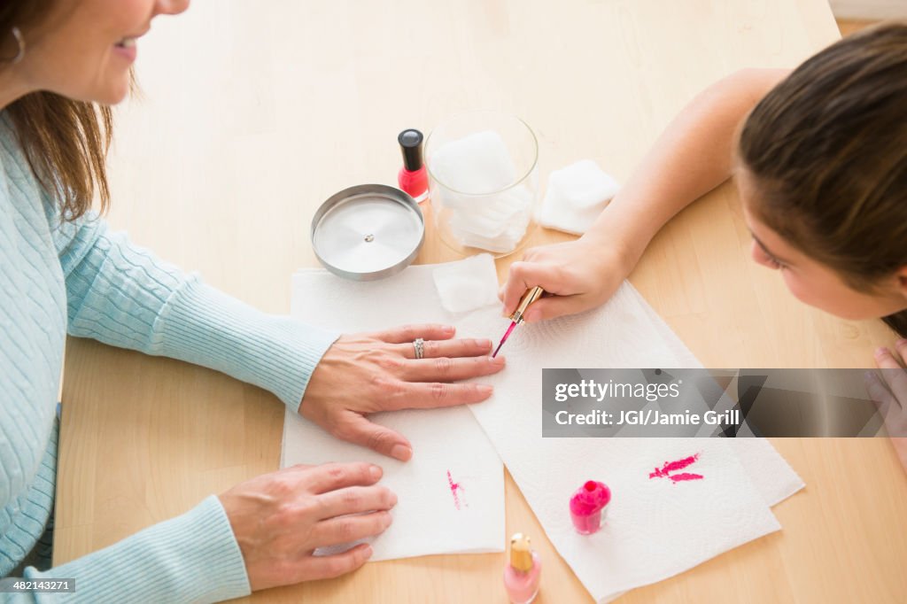 Caucasian girl giving mother a manicure