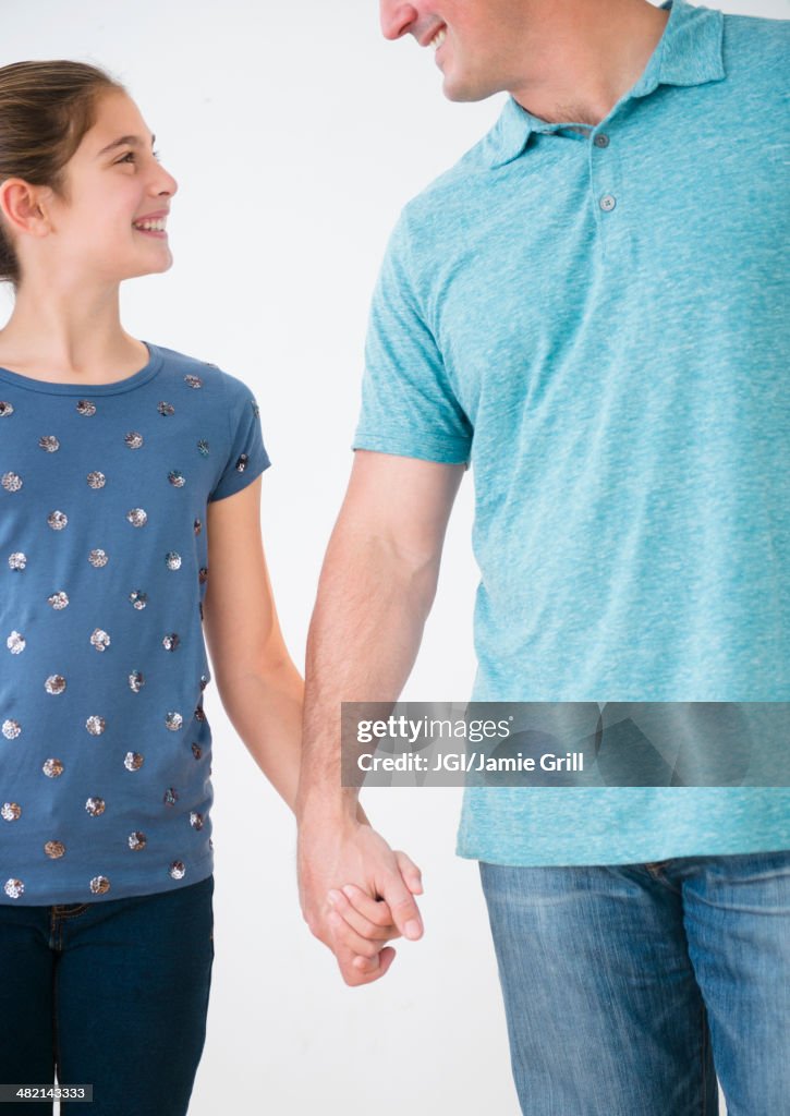 Smiling Caucasian father and daughter holding hands