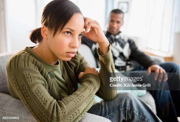 boyfriend watching frustrated girlfriend on sofa - arguing blacks stock-fotos und bilder