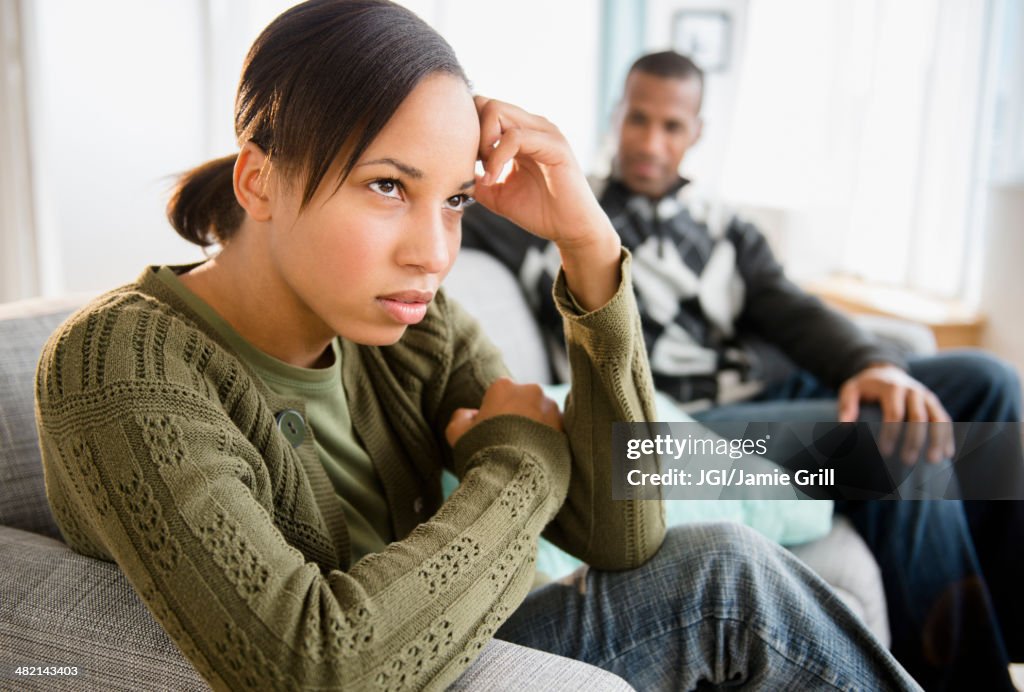 Boyfriend watching frustrated girlfriend on sofa