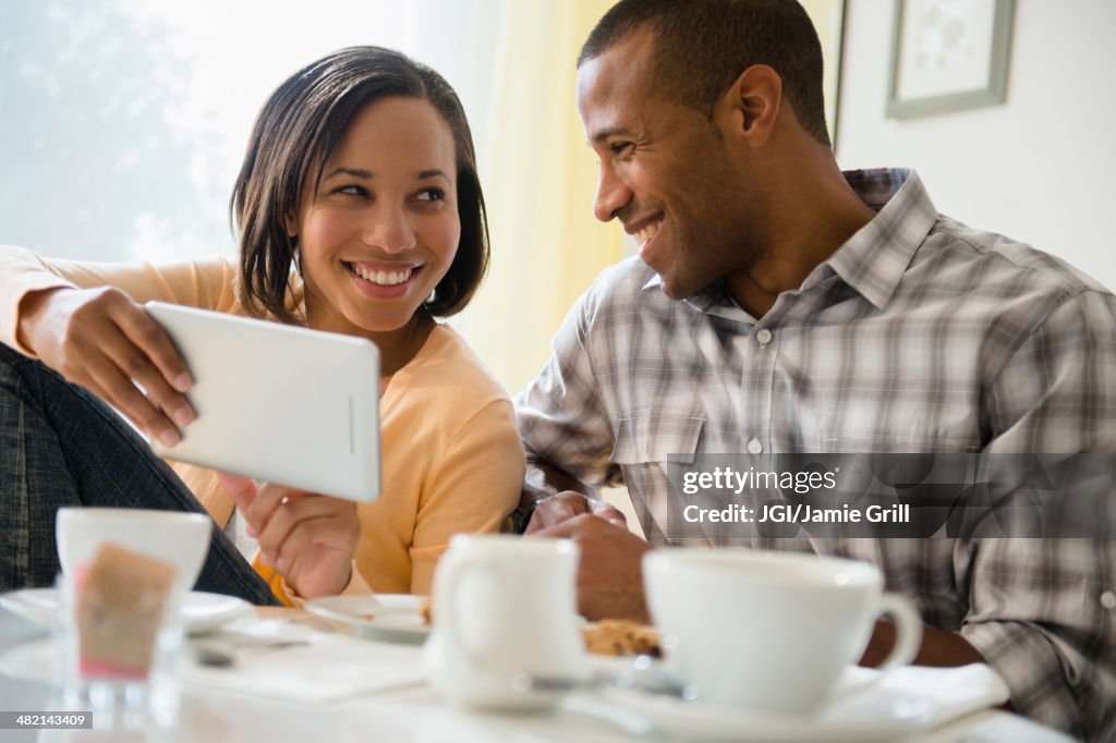 Happy couple drinking coffee and using digital tablet