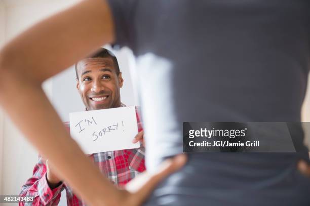 man showing 'i'm sorry' sign to angry girlfriend - apologize stockfoto's en -beelden
