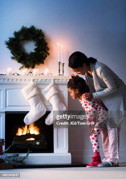 black mother and daughter looking at christmas stockings - black stockings stock pictures, royalty-free photos & images