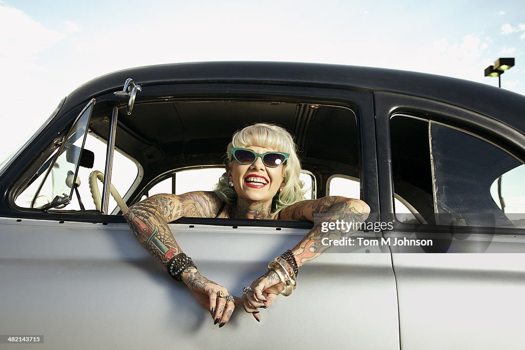 Woman with tattoos leaning out window of 1951 Chevy