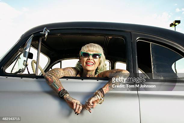 woman with tattoos leaning out window of 1951 chevy - a la moda stock pictures, royalty-free photos & images