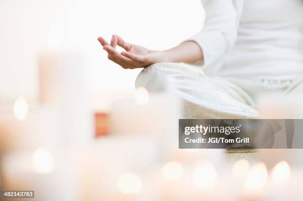 hispanic woman meditating in lotus position near lit candles - white candle stock pictures, royalty-free photos & images