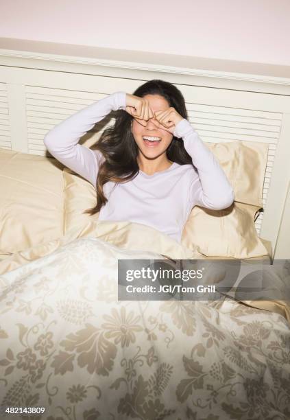 hispanic woman rubbing eyes in bed - reiben stock-fotos und bilder