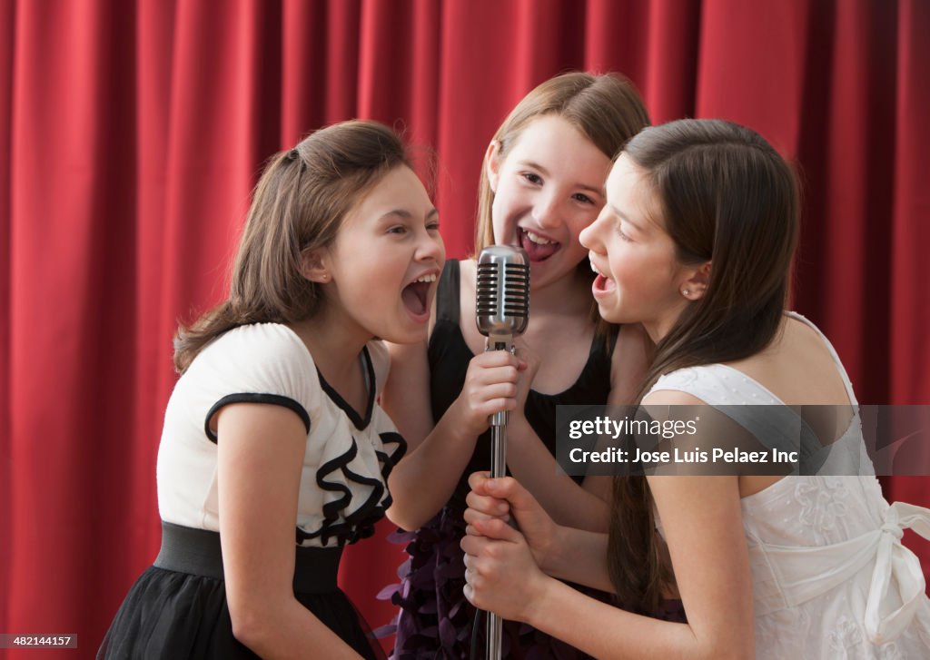 Caucasian girls singing into microphone on stage
