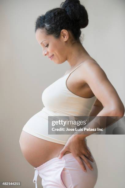 profile of pregnant mixed race woman showing stomach - pregnant isolated stock-fotos und bilder