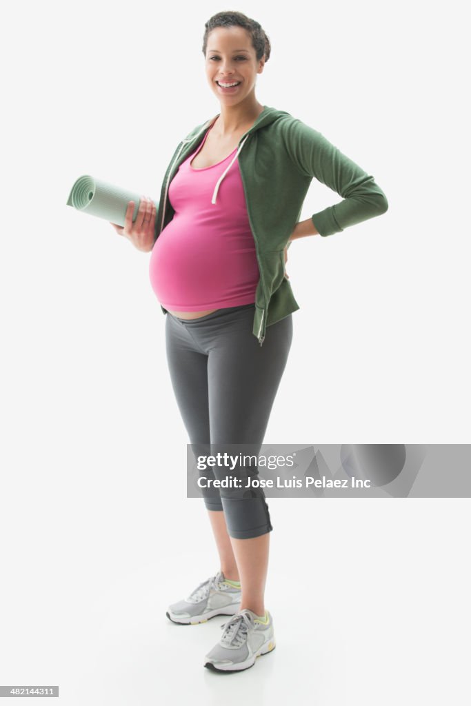 Portrait of pregnant mixed race woman with yoga mat