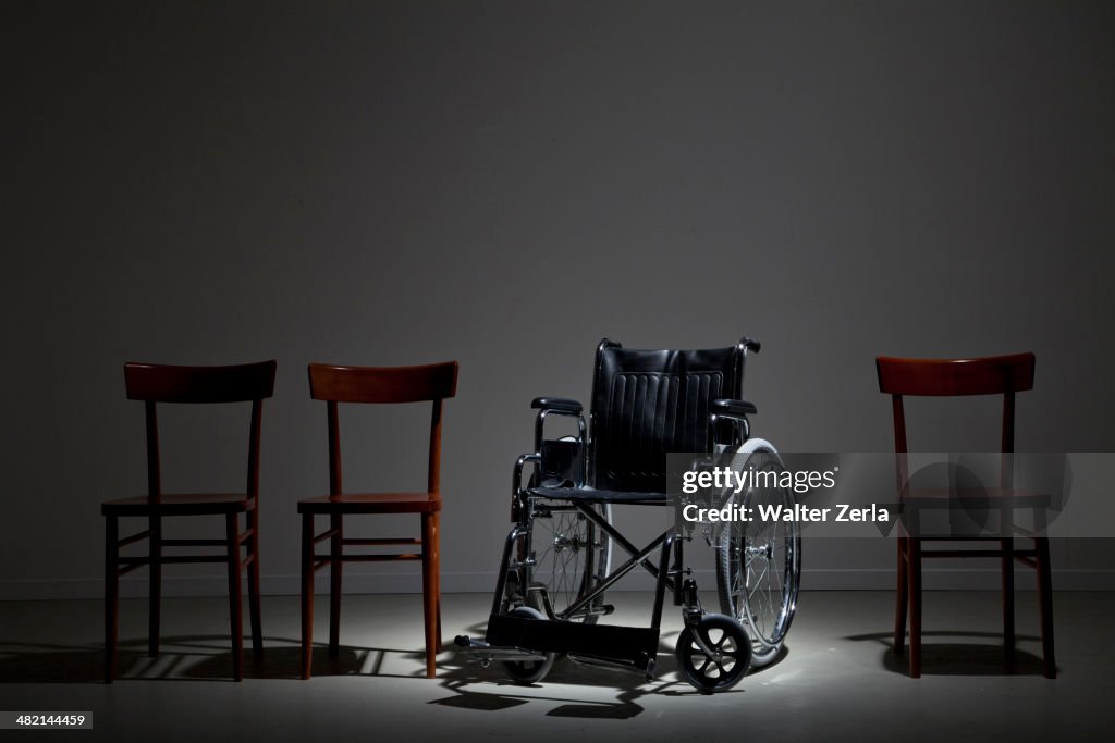 Wheelchair in line of wooden chairs