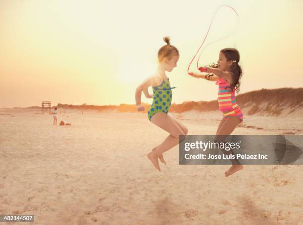 girls jumping rope on beach - seilspringen stock-fotos und bilder
