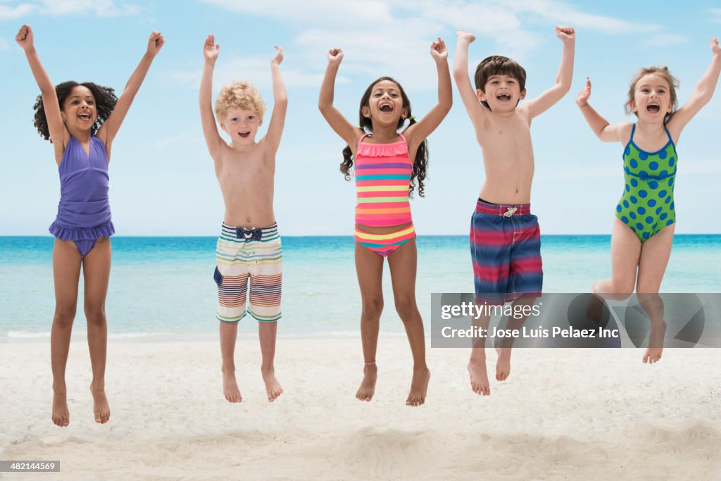Portrait of enthusiastic children jumping on beach