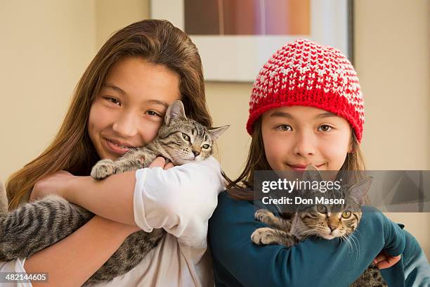 mixed race girls holding kittens - girls cuddling cat stock-fotos und bilder