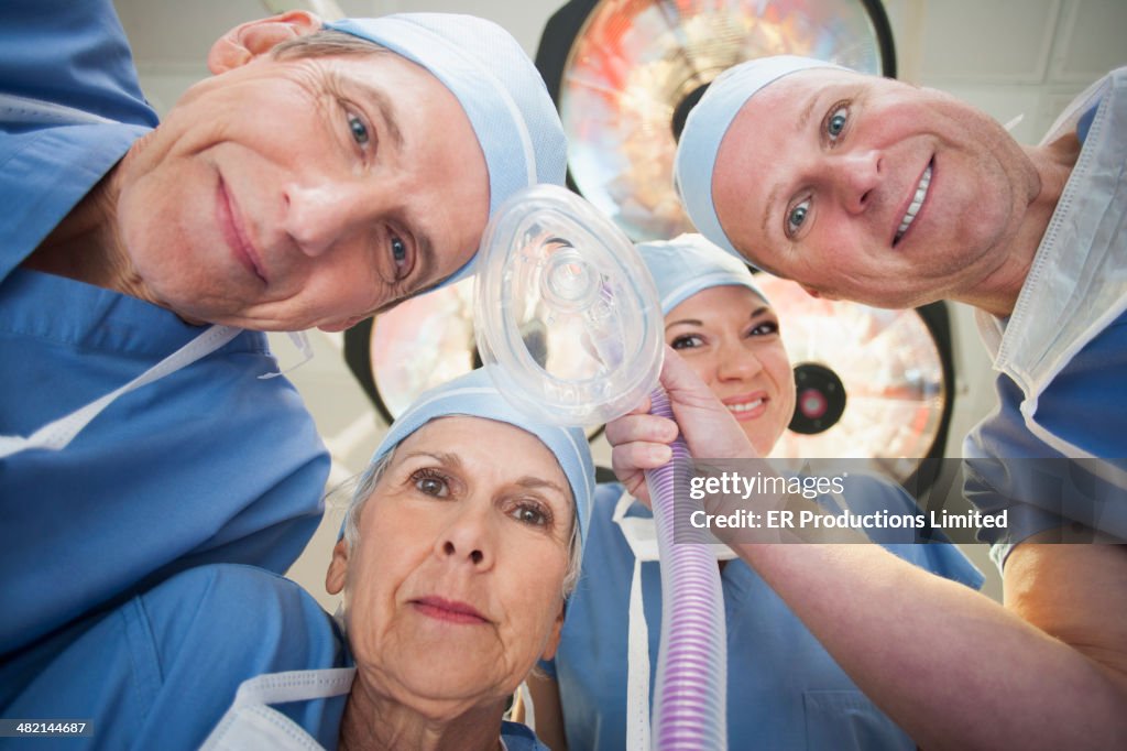 Caucasian surgeons holding oxygen mask in operating room