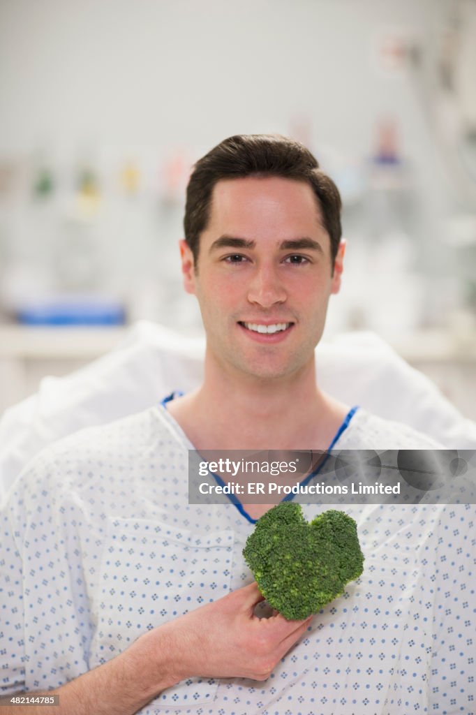 Caucasian man holding heart-shape broccoli in hospital