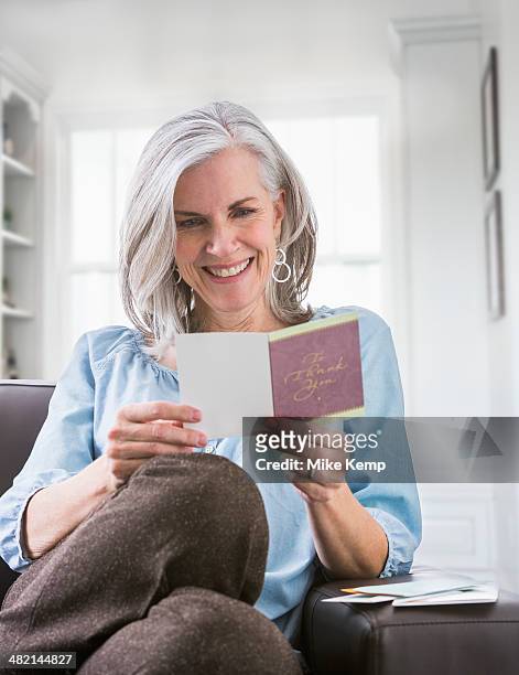 happy caucasian woman reading card on sofa - receiving card stock pictures, royalty-free photos & images