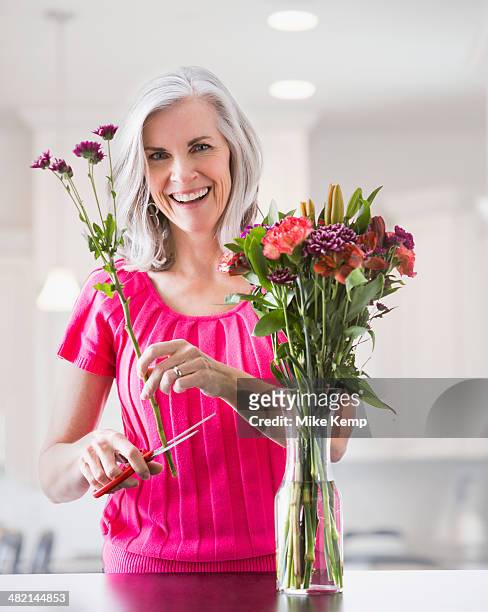 portrait of smiling caucasian woman arranging flowers - cut out happy ストックフォトと画像