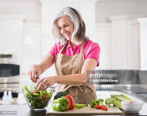 caucasian woman preparing salad in kitchen - groene paprika stockfoto's en -beelden