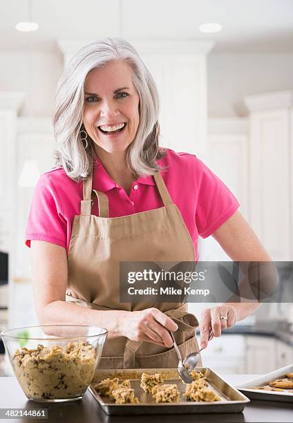 portrait of caucasian woman baking cookies - woman baking stock pictures, royalty-free photos & images