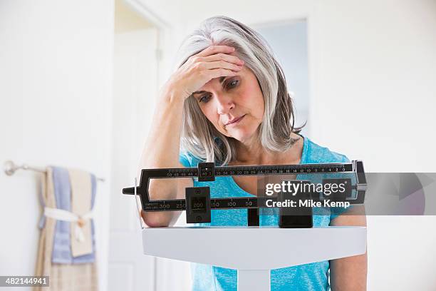 unhappy caucasian woman standing on weight scale - body conscious stock pictures, royalty-free photos & images
