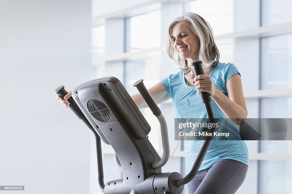 Happy Caucasian woman on elliptical trainer at gym