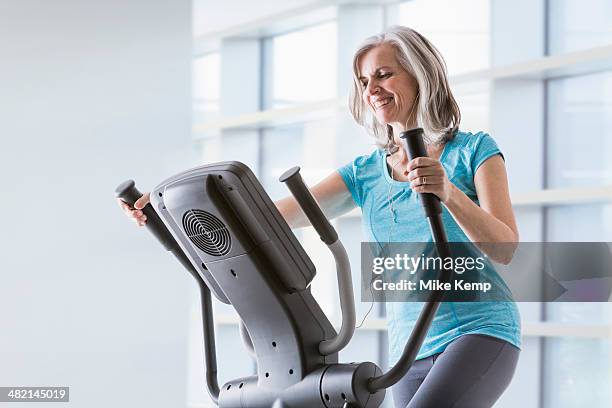 happy caucasian woman on elliptical trainer at gym - トレッドミル　女性 ストックフォトと画像