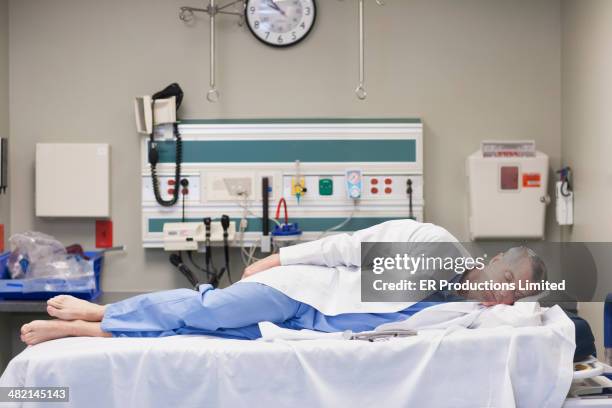 caucasian doctor sleeping on hospital bed - solo un uomo maturo foto e immagini stock