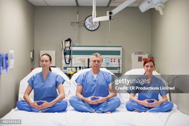 nurses meditating on hospital beds - three people in bed stock pictures, royalty-free photos & images