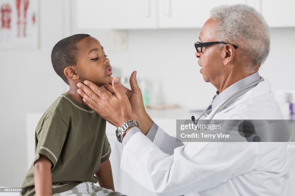 Doctor checking boy's glands in doctor's office