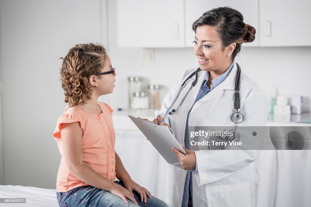 Doctor with clipboard talking to girl in doctor's office