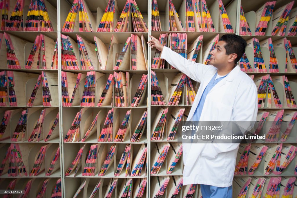 Hispanic doctor pointing at medical files in hospital