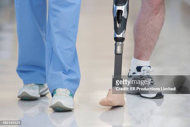 nurse helping man walk with prosthetic leg - equipo protésico fotografías e imágenes de stock