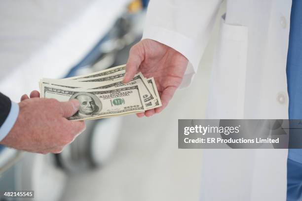 doctor and businessman exchanging money in hospital - bribing stockfoto's en -beelden