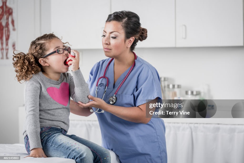 Nurse helping girl with asthma inhaler in doctor's office