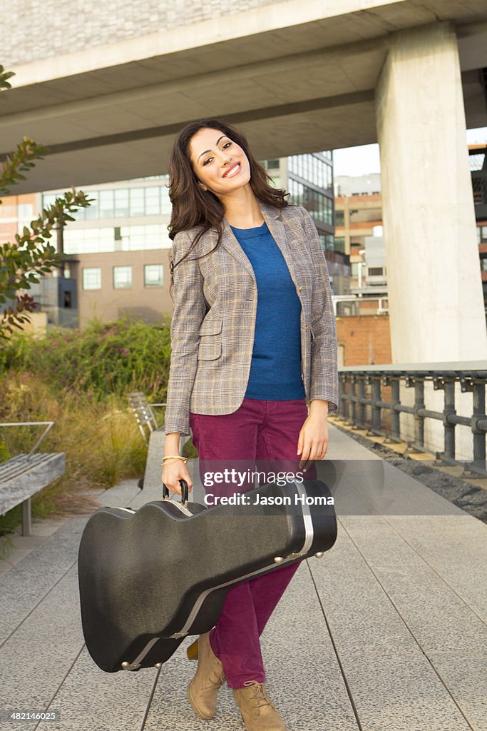 Mixed race woman carrying guitar case
