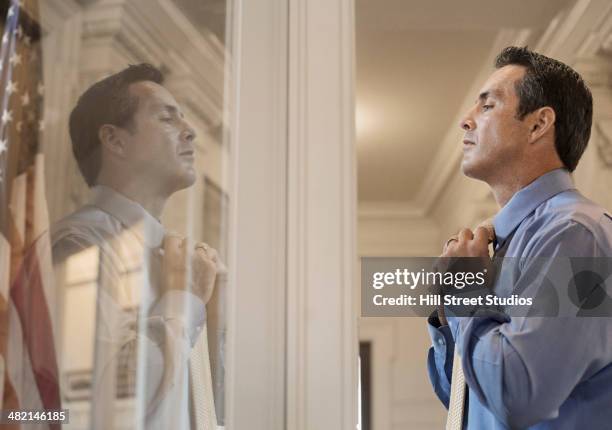 caucasian politician adjusting his tie in window - government accountability office stock pictures, royalty-free photos & images