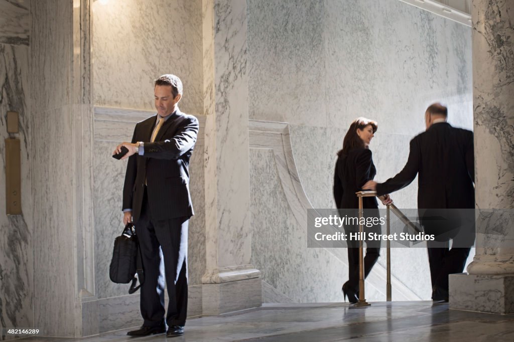 Caucasian politician checking watch in government building