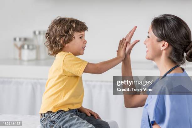 nurse high fiving boy in doctor's office - criança enfermagem imagens e fotografias de stock