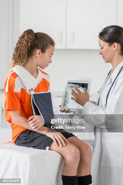 doctor showing girl with arm in sling x-ray on digital tablet - data vulnerability stock pictures, royalty-free photos & images